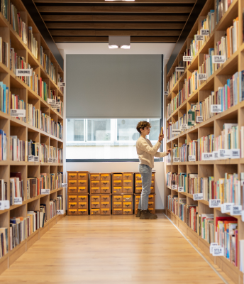 A robot stands in front of the shelves, ready to help gather and organize items in the facility.